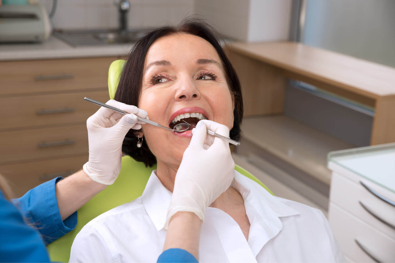 Brunette woman smiles while receiving a dental checkup at her dentist in Bellevue, WA
