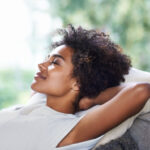 Curly-haired woman relaxes during her recovery from oral surgery
