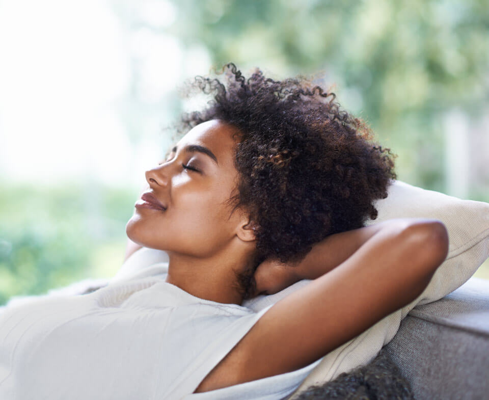 Curly-haired woman relaxes during her recovery from oral surgery in Bellevue