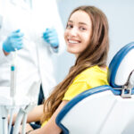 Young brunette woman in a yellow shirt smiles at her dentist in Bellevue, WA