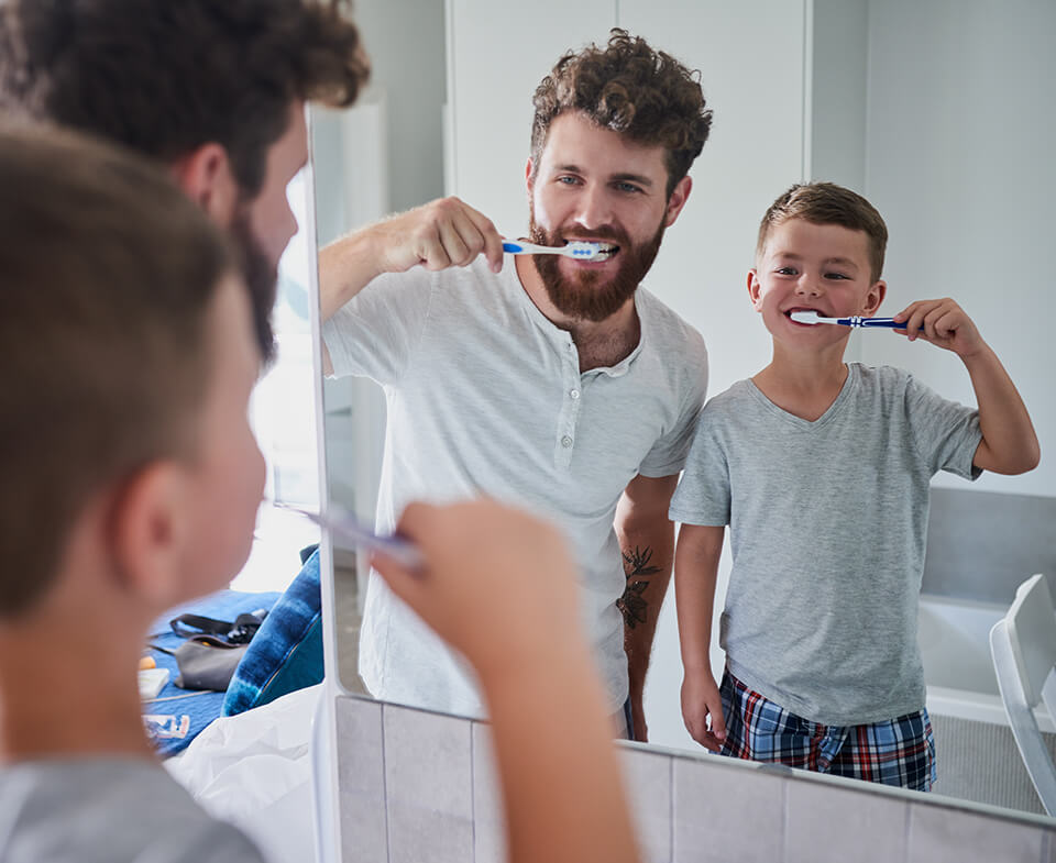 father and son brushing their teeth together