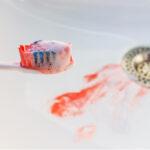 A bloody toothbrush over a bloody sink from bleeding gums due to gum disease