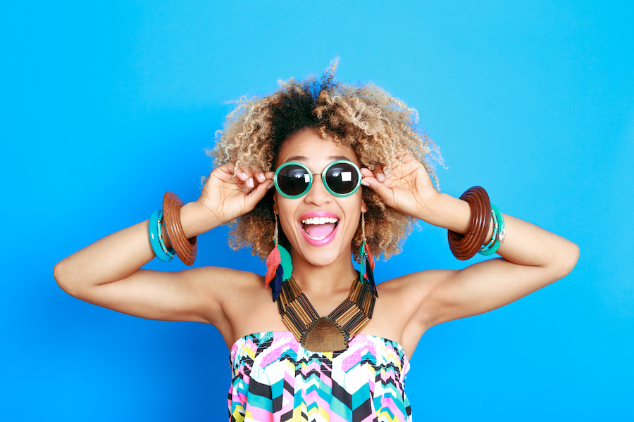 Black woman smiles while wearing sunglasses