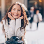Smiling young woman outdoors in the city undergoing orthodontic treatment.