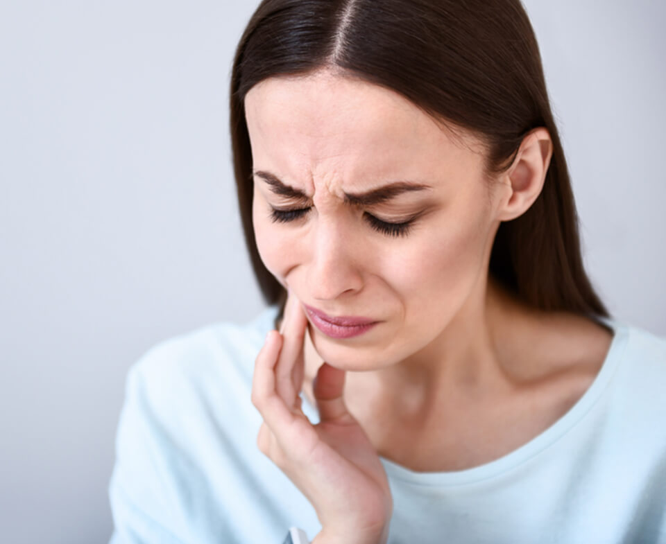 woman holding her jaw in pain